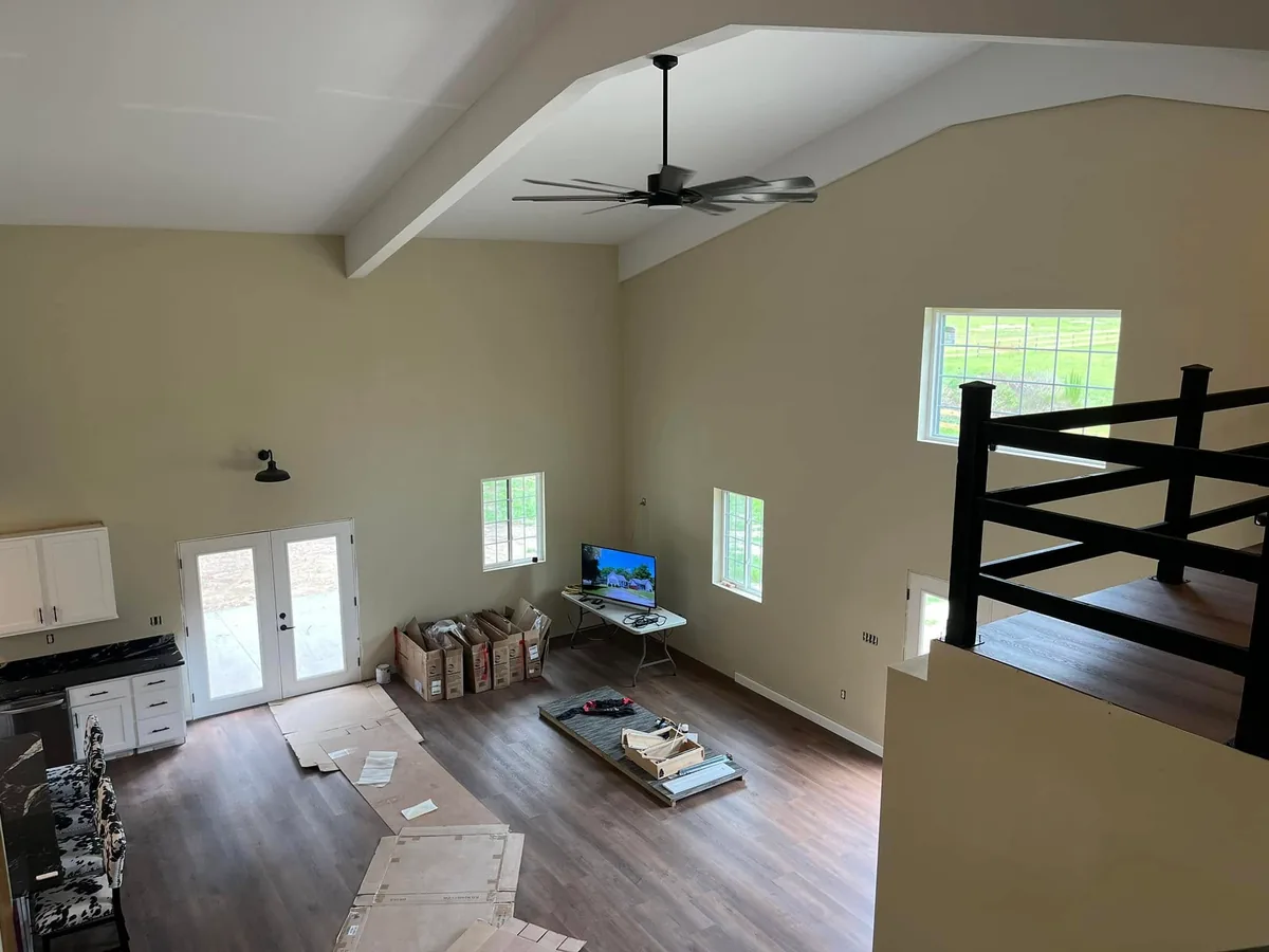 Barndominium great room seen from the loft with a ceiling beam and fan