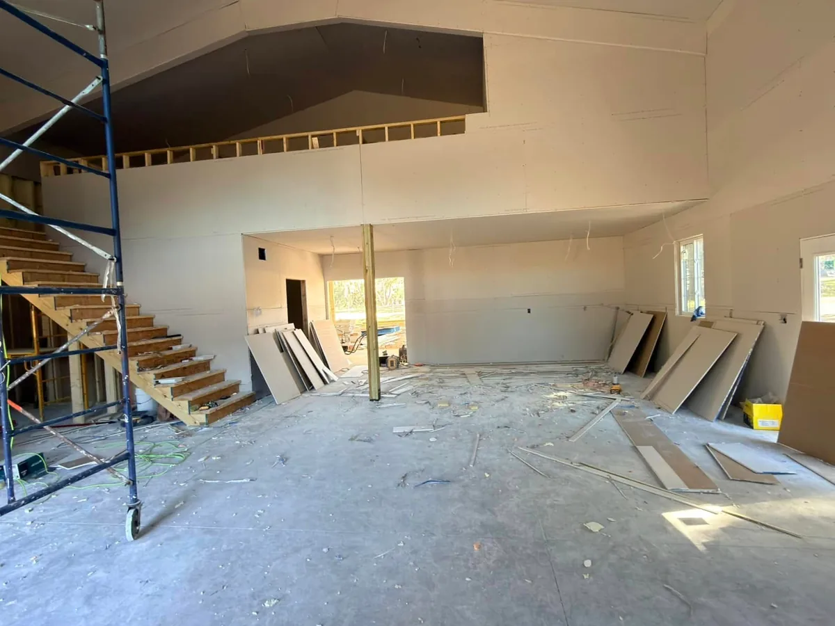 Barndominium interior at the drywall stage with the staircase and scaffolding