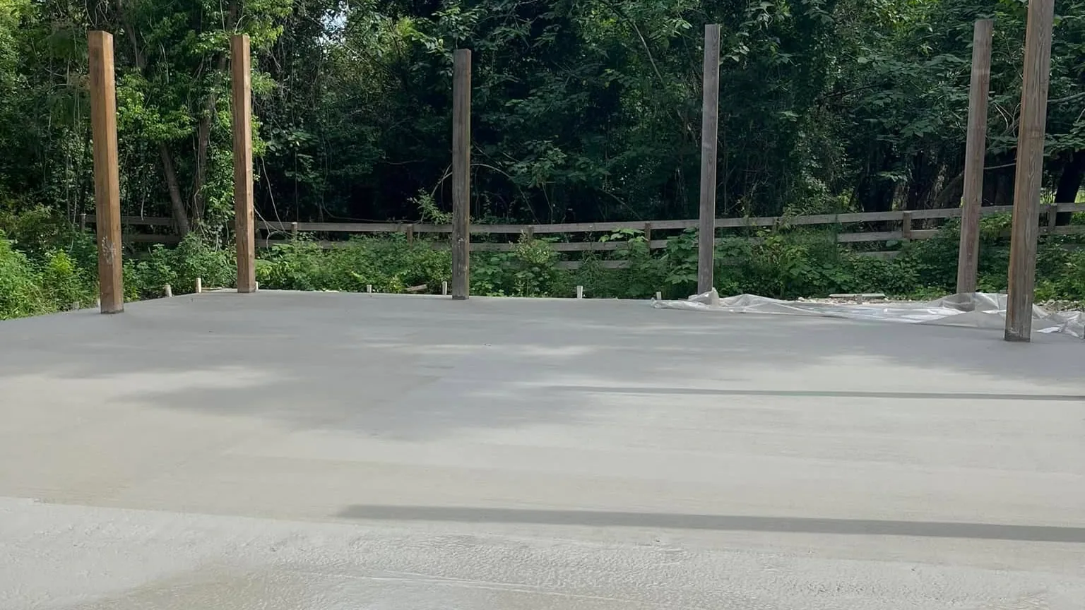 Freshly poured concrete slab with barn posts set around it