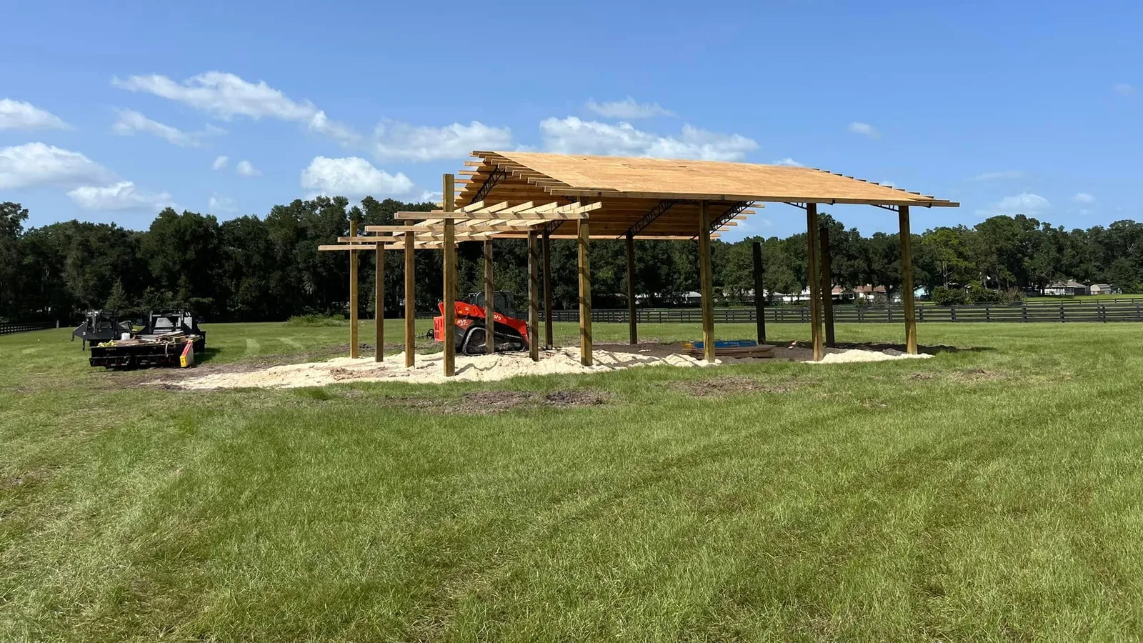 Pole barn pavilion framed on a sand pad in an open pasture