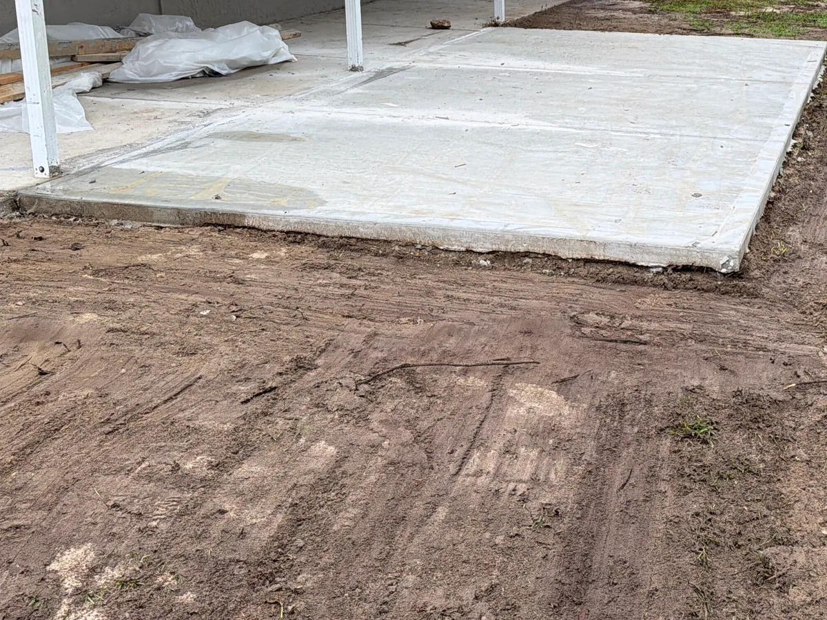 New concrete slab poured beside a building with the ground graded around it