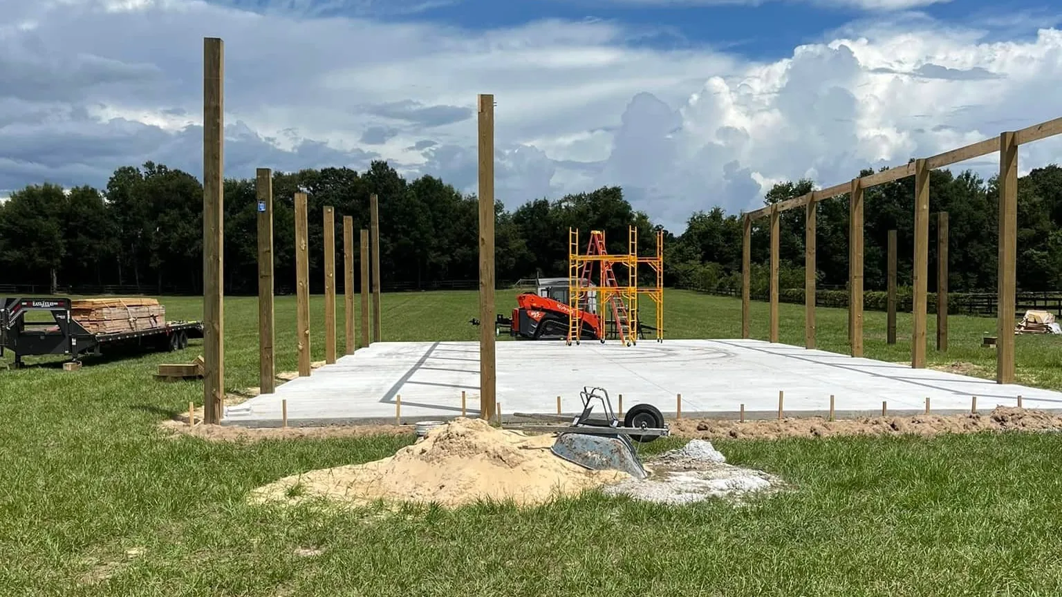 Posts and beams set around a finished concrete slab in a pasture