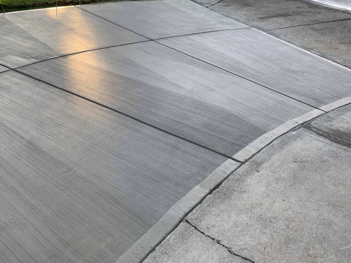 New broom finish concrete driveway with control joints meeting the curb apron
