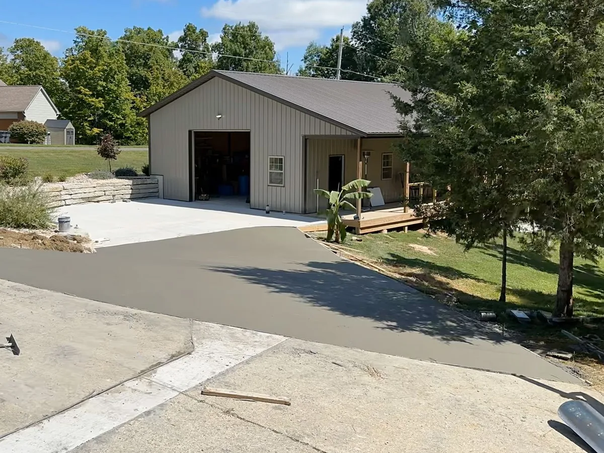 Freshly poured concrete driveway leading to a metal garage building