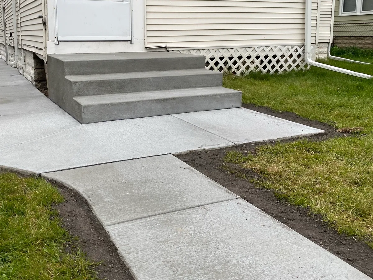 New concrete sidewalk and front steps beside a house