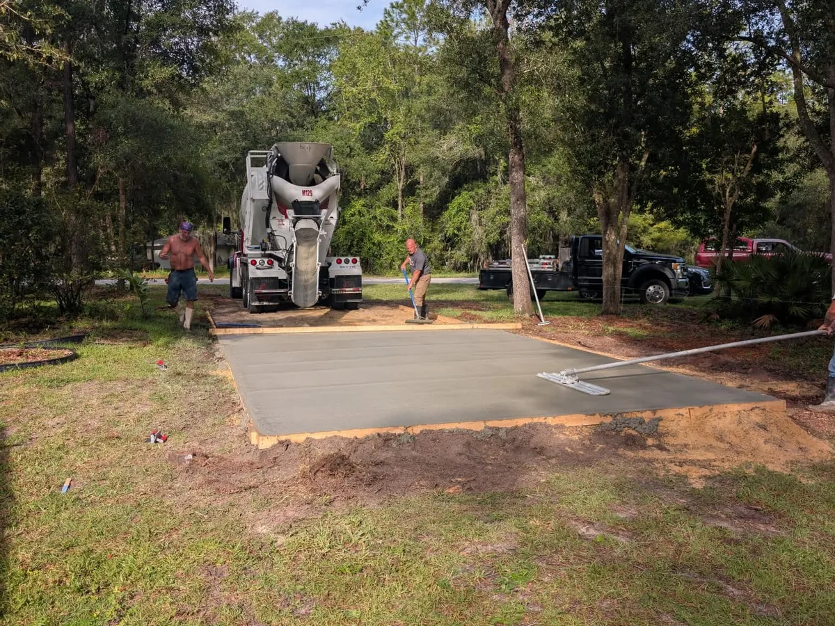 Crew placing and floating concrete from a mixer truck into a formed pad