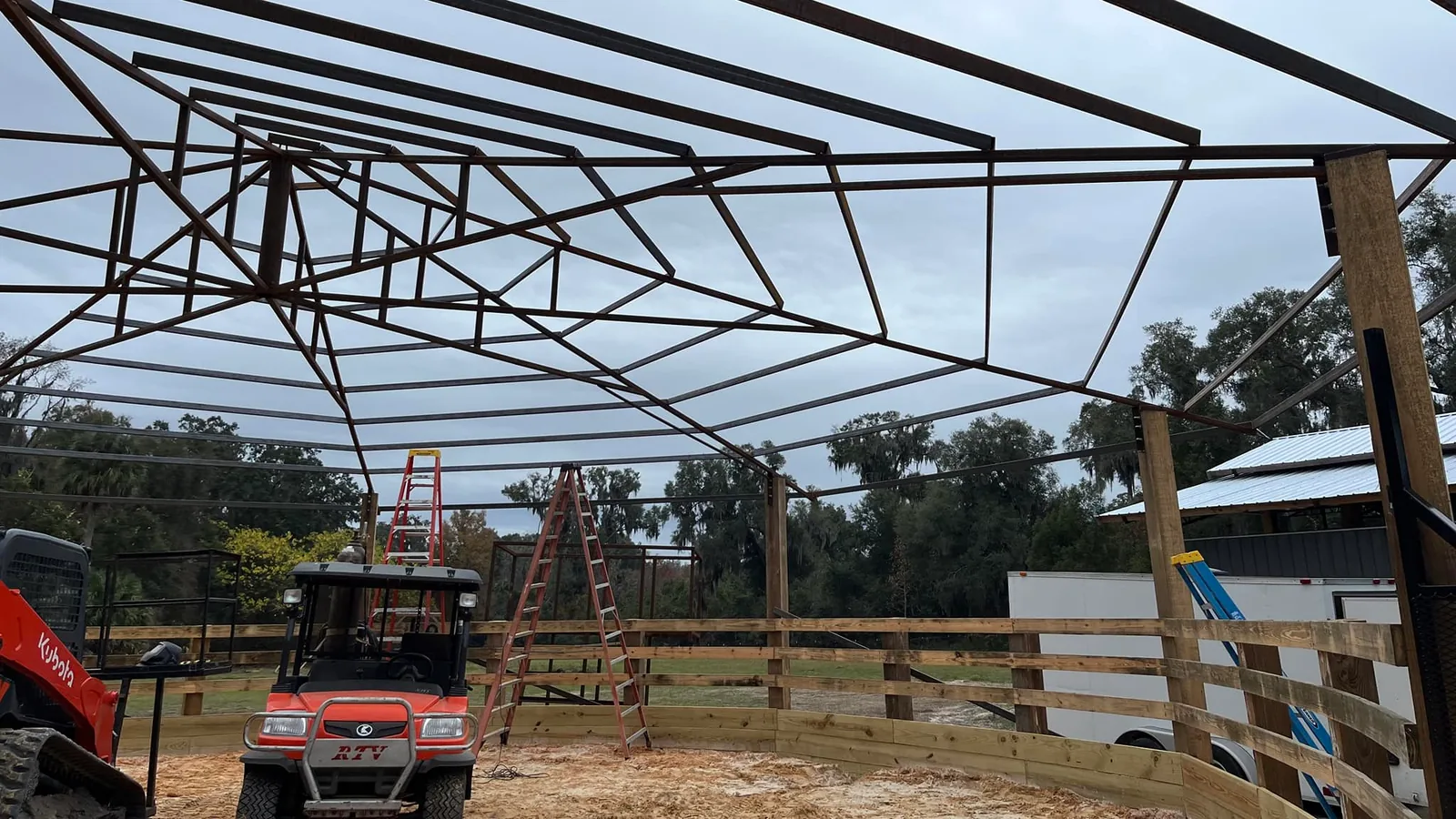 Steel roof frame of a covered round pen with ladders and a utility vehicle