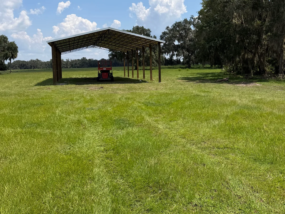 Open sided equipment shelter pole barn standing in a pasture