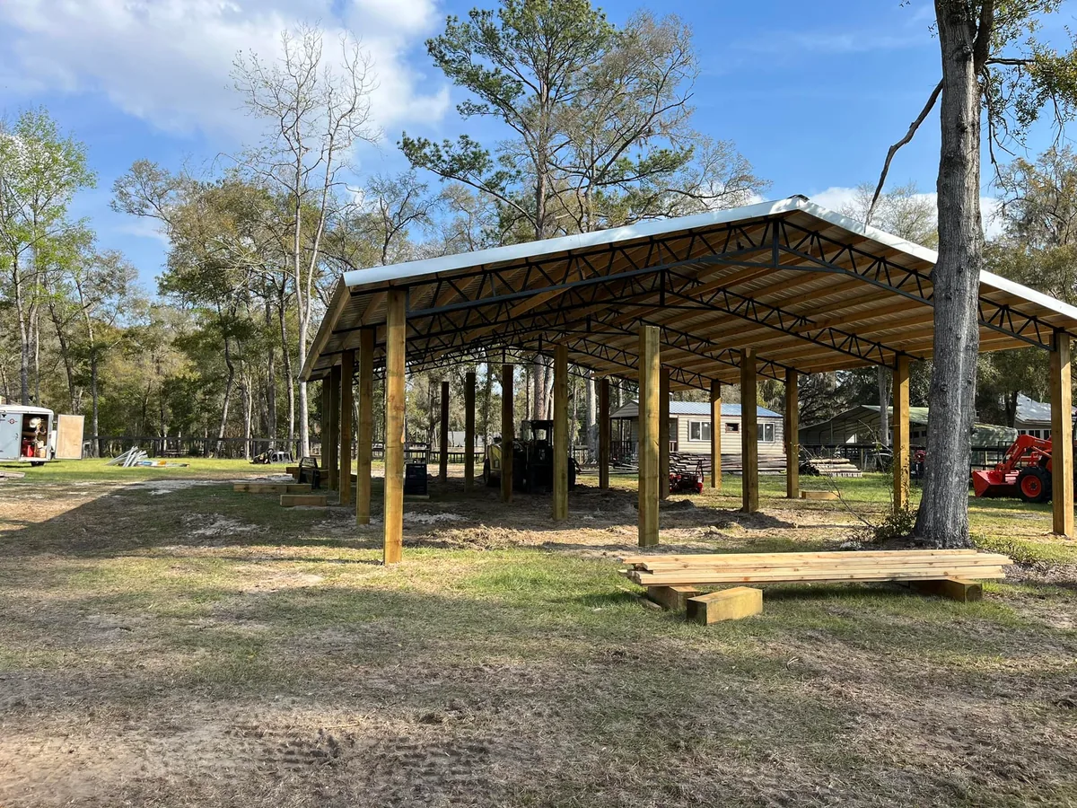 Finished open pole barn with black steel trusses and a metal roof